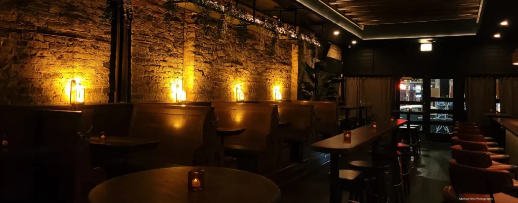 Dimly lit bar with wooden tables and brick walls.
